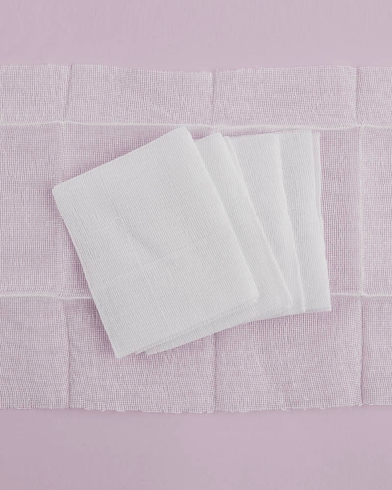 white cotton gauze pads overlapping each other on a pink background